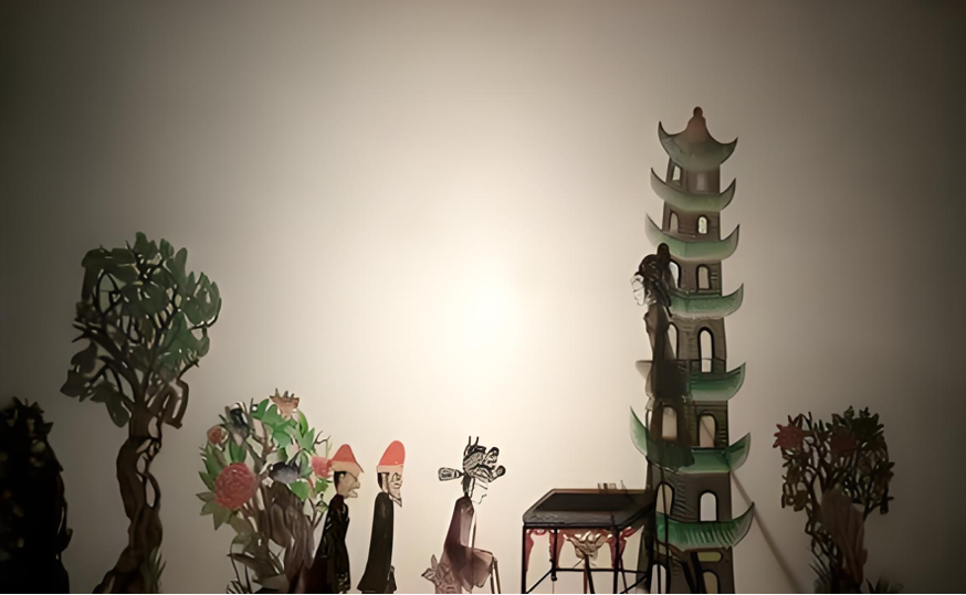 A backlit shadow-puppet scene with three figures, flowering trees, and a tall pagoda.